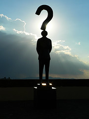 Man standing with sunset behind and question mark overhead